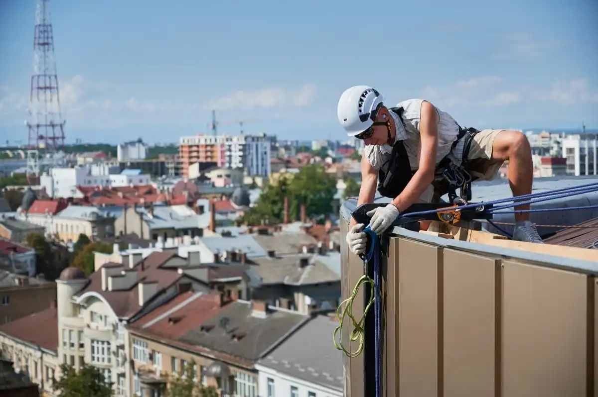 Alpinist utilitar care fixează corzile pe parapetul unui acoperiș