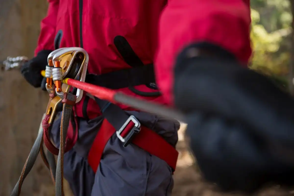 Dispozitiv de coborâre prins pe coardă, în mâna unui alpinist