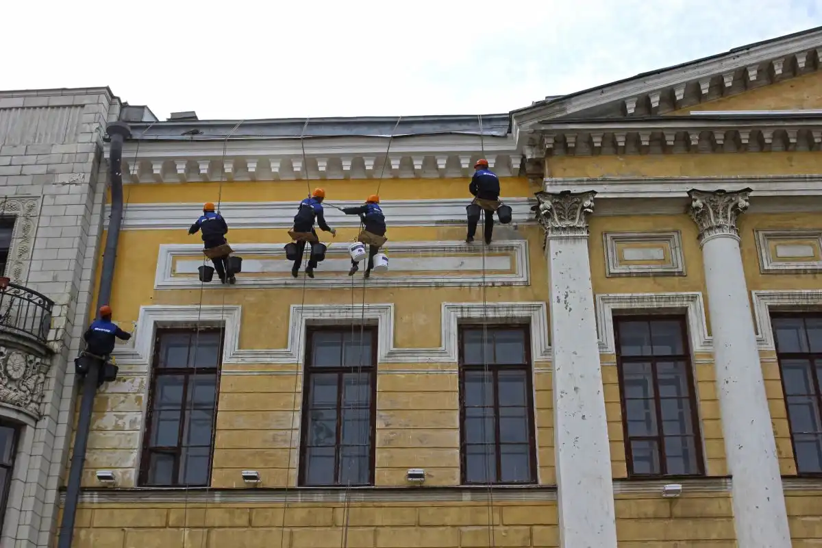 Alpiniști utilitari pe fațada unei clădiri istorice cu coloane