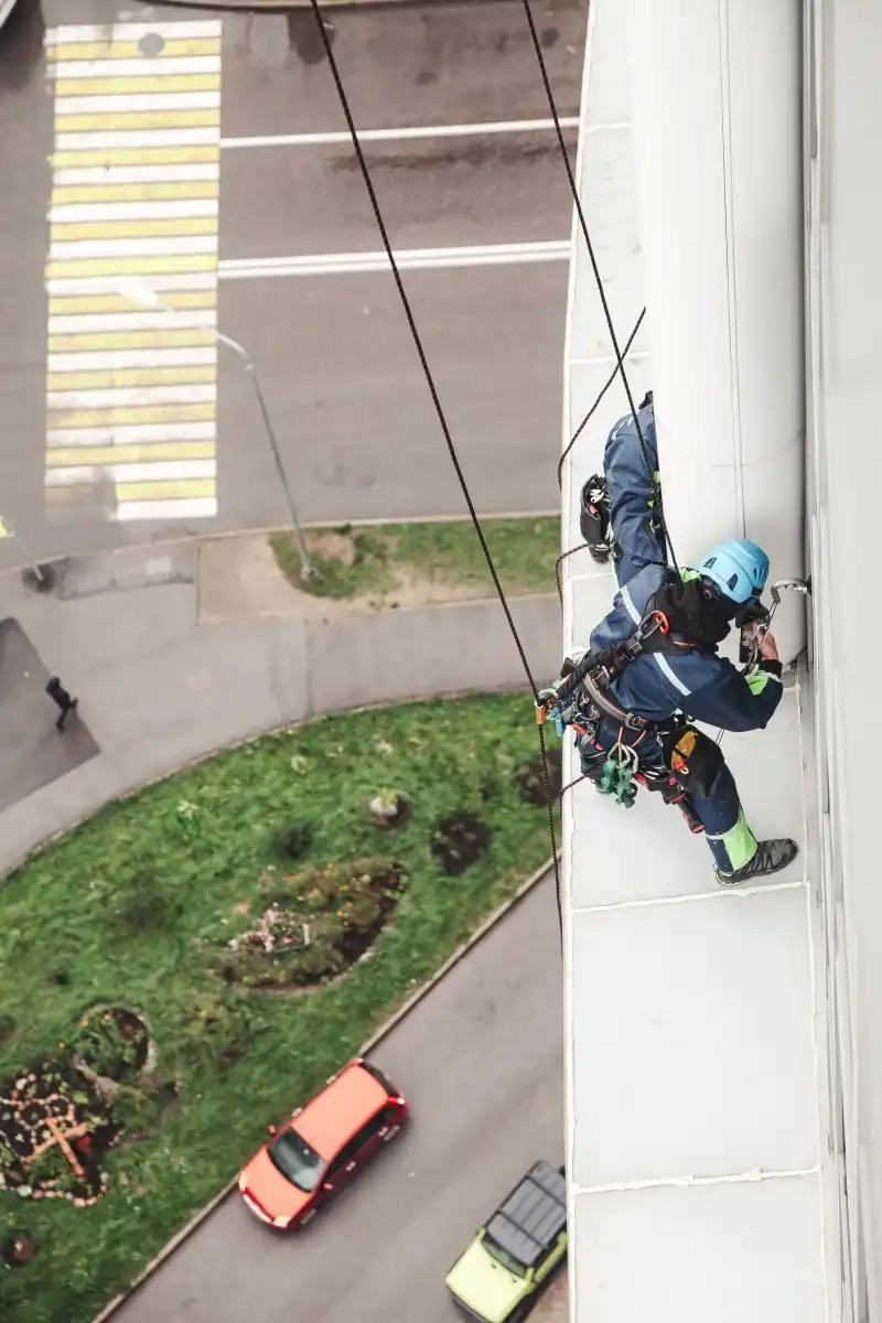 Alpinist utilitar pe fațada unei clădiri înalte, văzut de sus