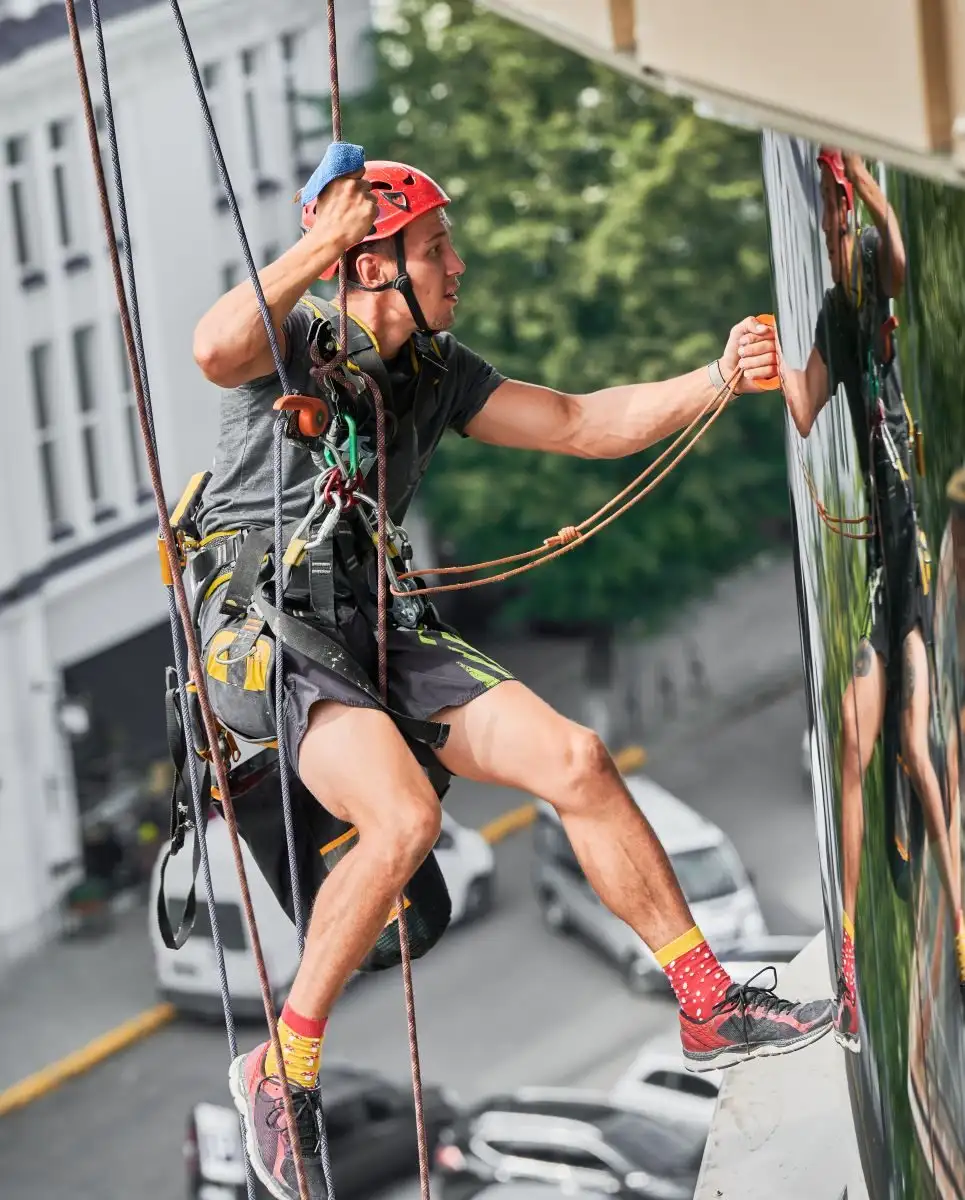 Alpinist utilitar în corzi care curăță un geam mare