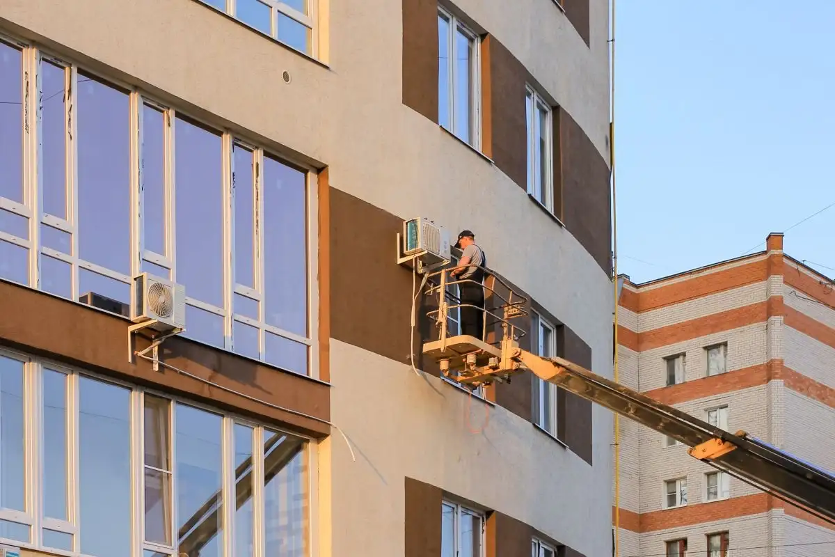 Nacelă cu braț telescopic lângă fațada unei clădiri de locuințe