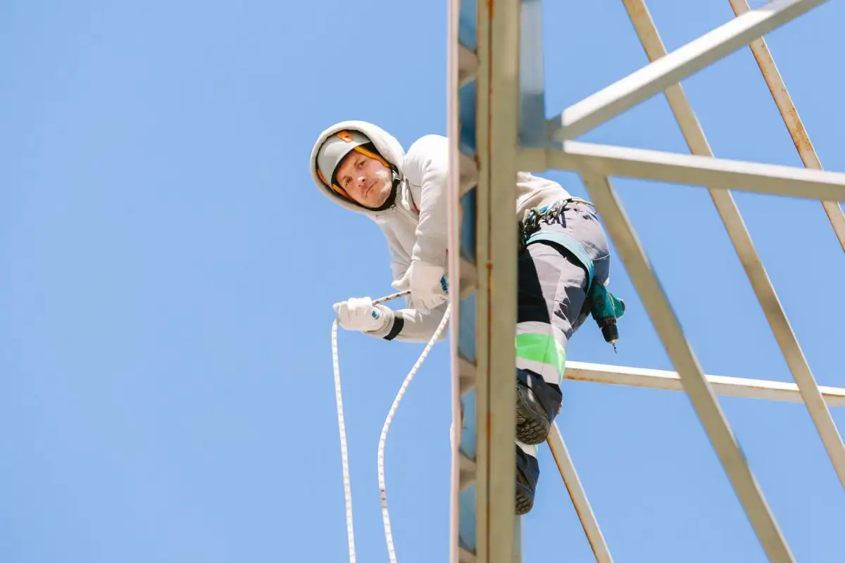 Alpinist utilitar care coboară pe o structură metalică cu zăbrele